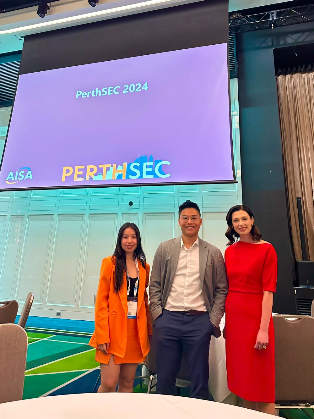 Hoang and Huu Nguyen from CyberNIQ with a fellow attendee in front of the PerthSEC 2024 screen
