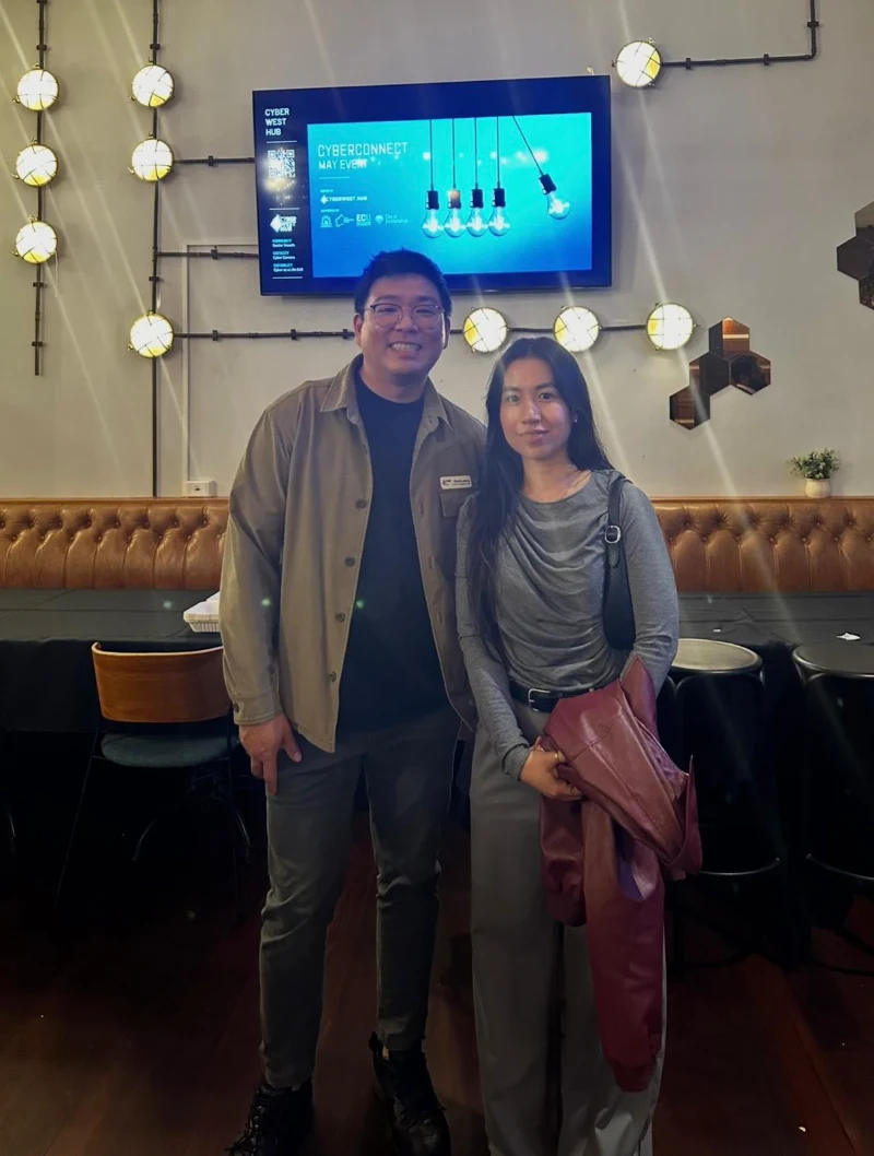 Two CyberNIQ team members in front of the CyberConnect May event screen