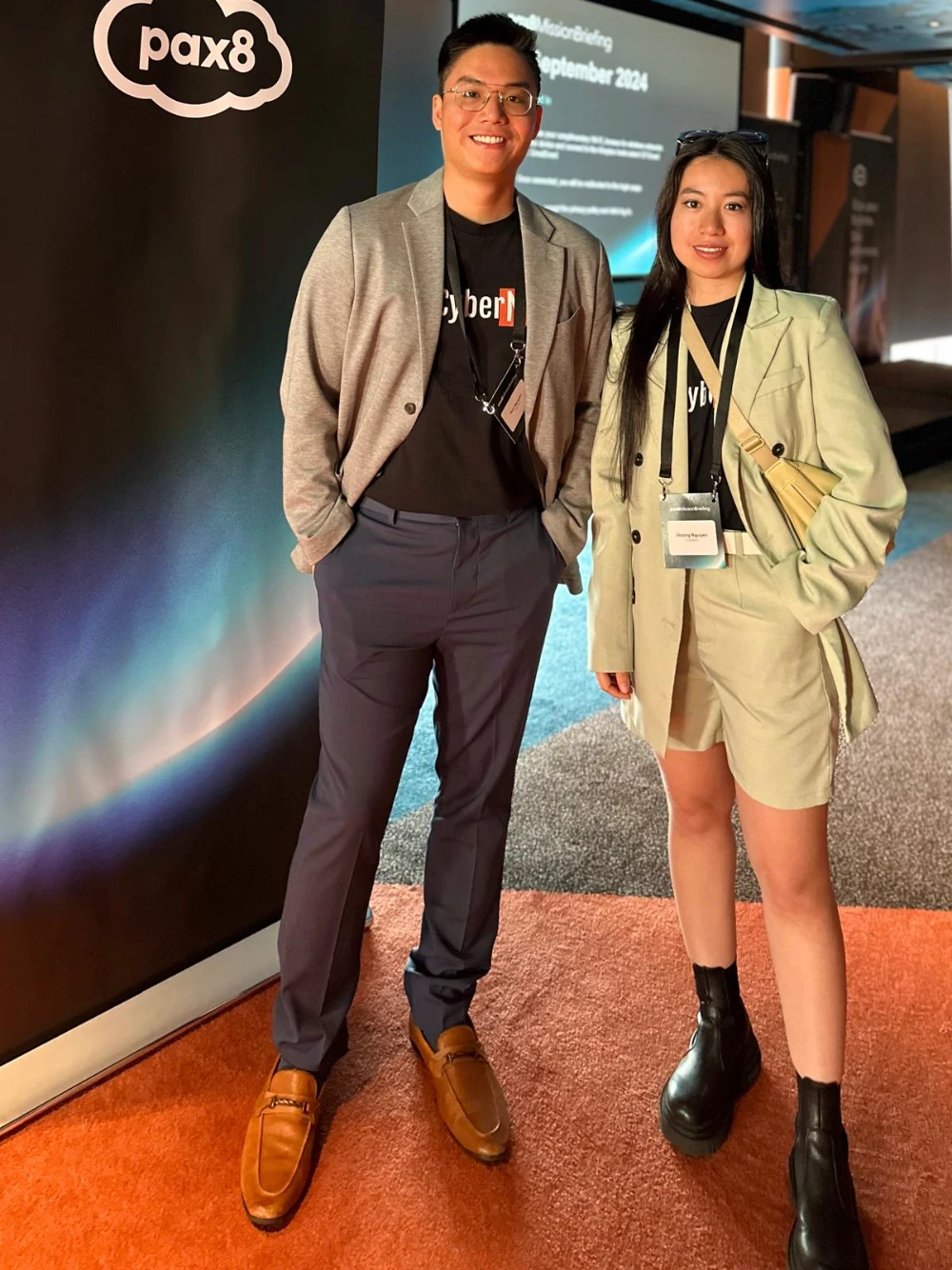 Huu and Hoang from CyberNIQ in front of the Pax8 backdrop