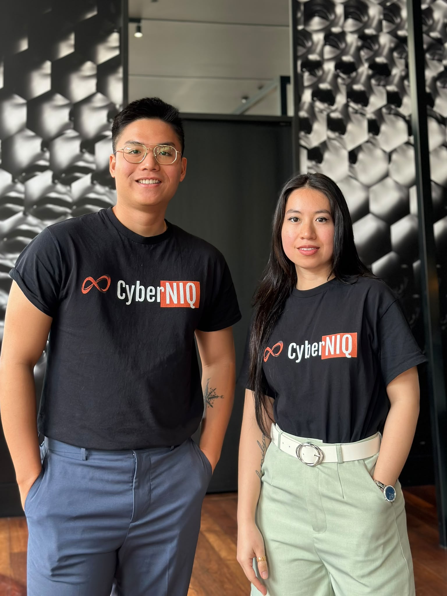 Two CyberNIQ team members in CyberNIQ t-shirts